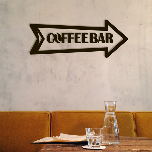 Metal sign pointing to a coffee bar above a table with a glass and carafe. Acrylic wall decor - Vibewall