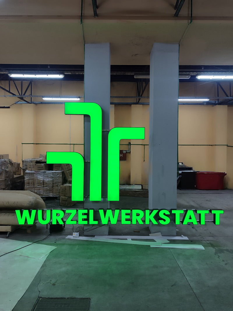 Green logo and text sign 'WURZELWERKSTATT' in a workshop setting
