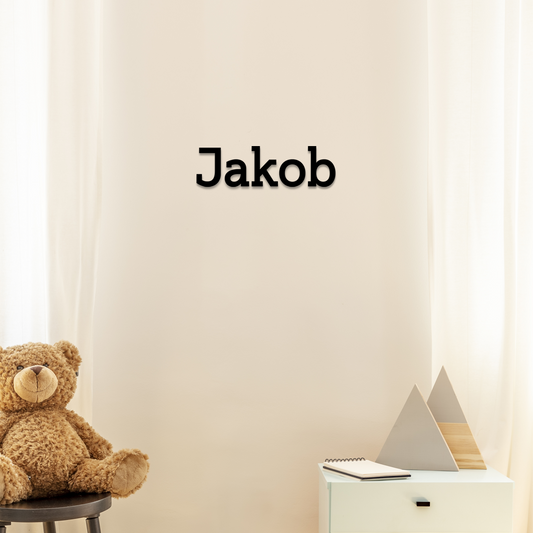 Teddy bear on a chair next to a desk with a nameplate reading 'Jakob' on a light-colored wall. Acrylic wall dekor - Vibewall