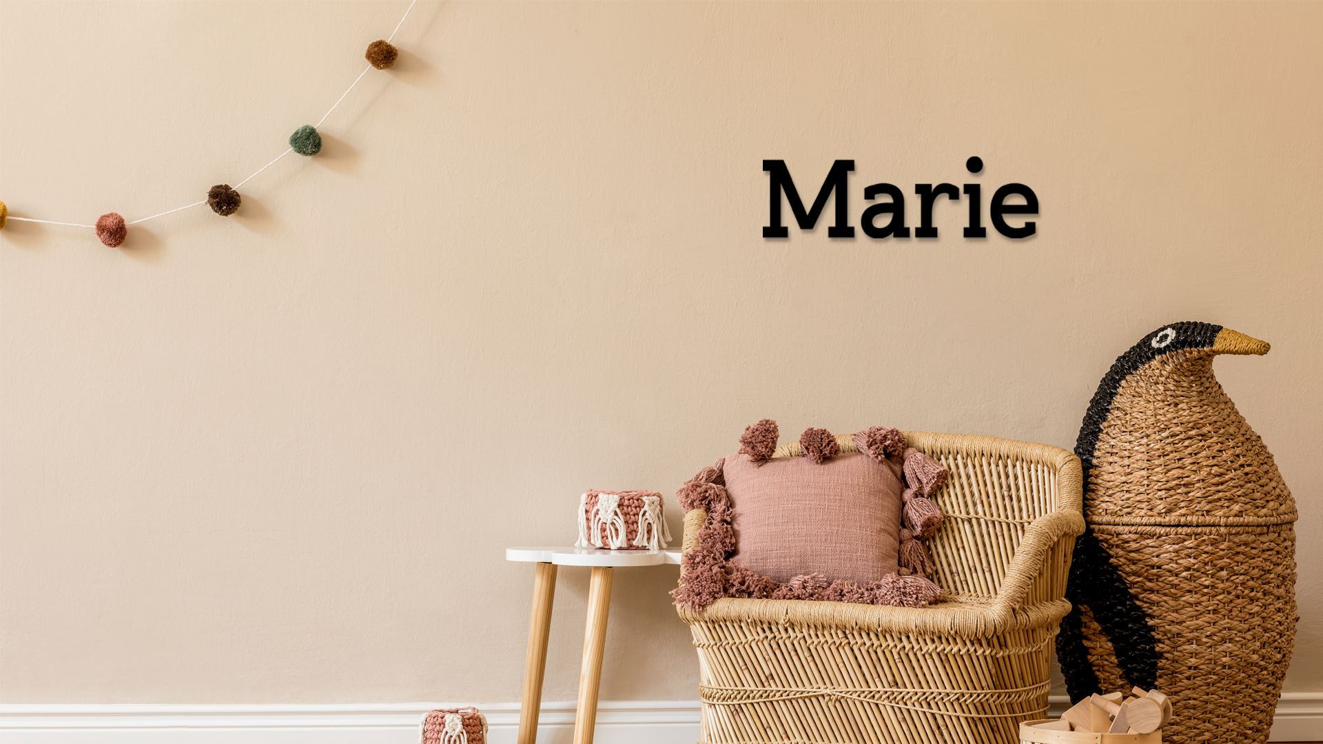 Decorative room with wicker chair, pink pillow, and decorative penguin against a beige wall with 'Marie' text. Acrylic wall decor - Vibewall