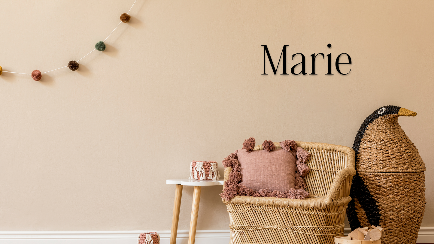 Wicker chair with pink cushion and decorative items against a beige wall with 'Marie' text - Acrylic wall decor - Vibewall