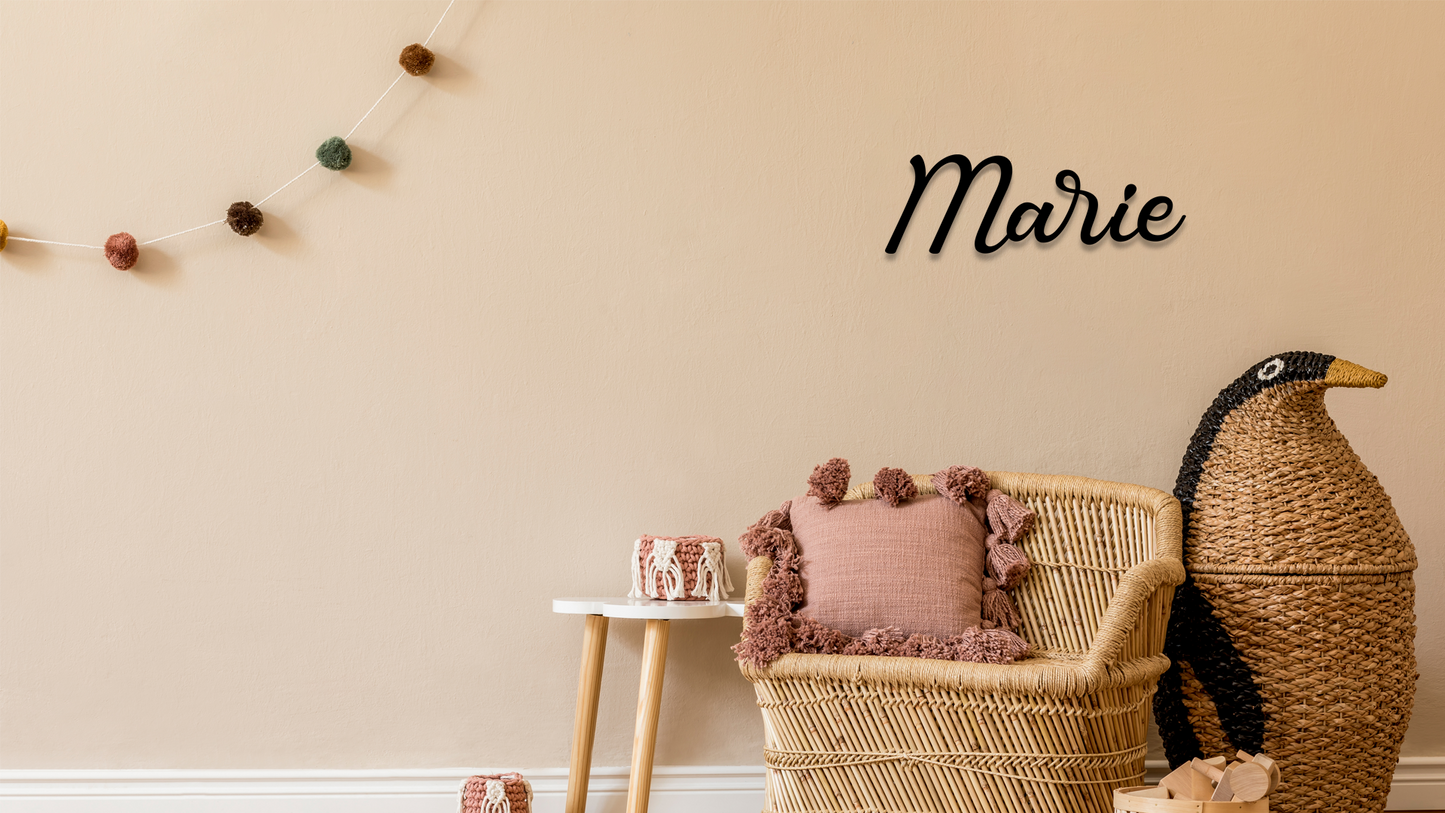 Wicker chair with pink cushion, small table, and decorative penguin against a beige wall with 'Marie' decal. Acrylic wall decor - Vibewall