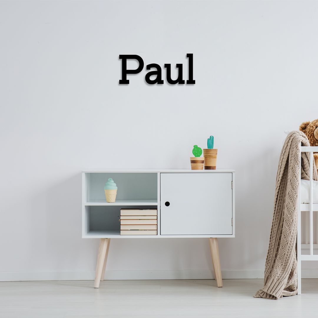 White cabinet with decorative items against a light gray wall, with 'Paul' displayed above. Acrylic wall decor - Vibewall
