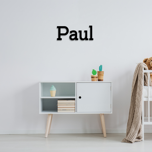 White cabinet with decorative items against a light gray wall, with 'Paul' displayed above. Acrylic wall decor - Vibewall