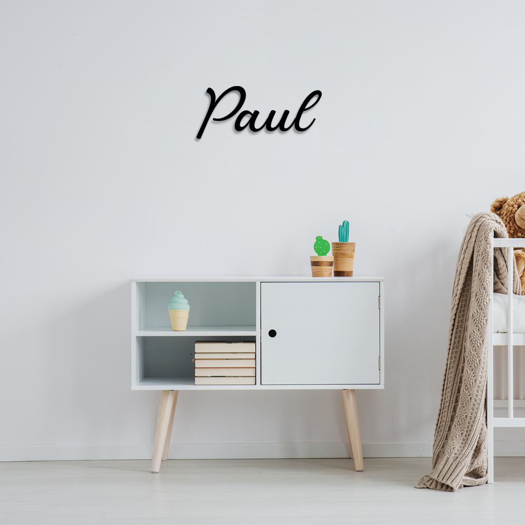White cabinet with decorative items against a light gray wall with 'Paul' text. Acrylic wall dekor - Vibewall