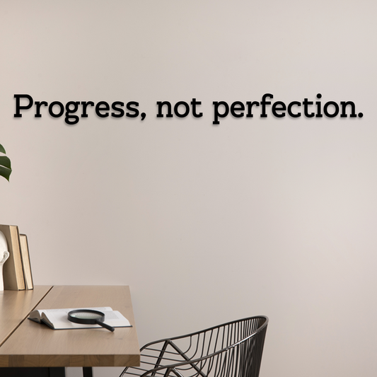 Wall with 'Progress, not perfection.' quote above a desk and chair. Acrylic wall decor - Vibewall
