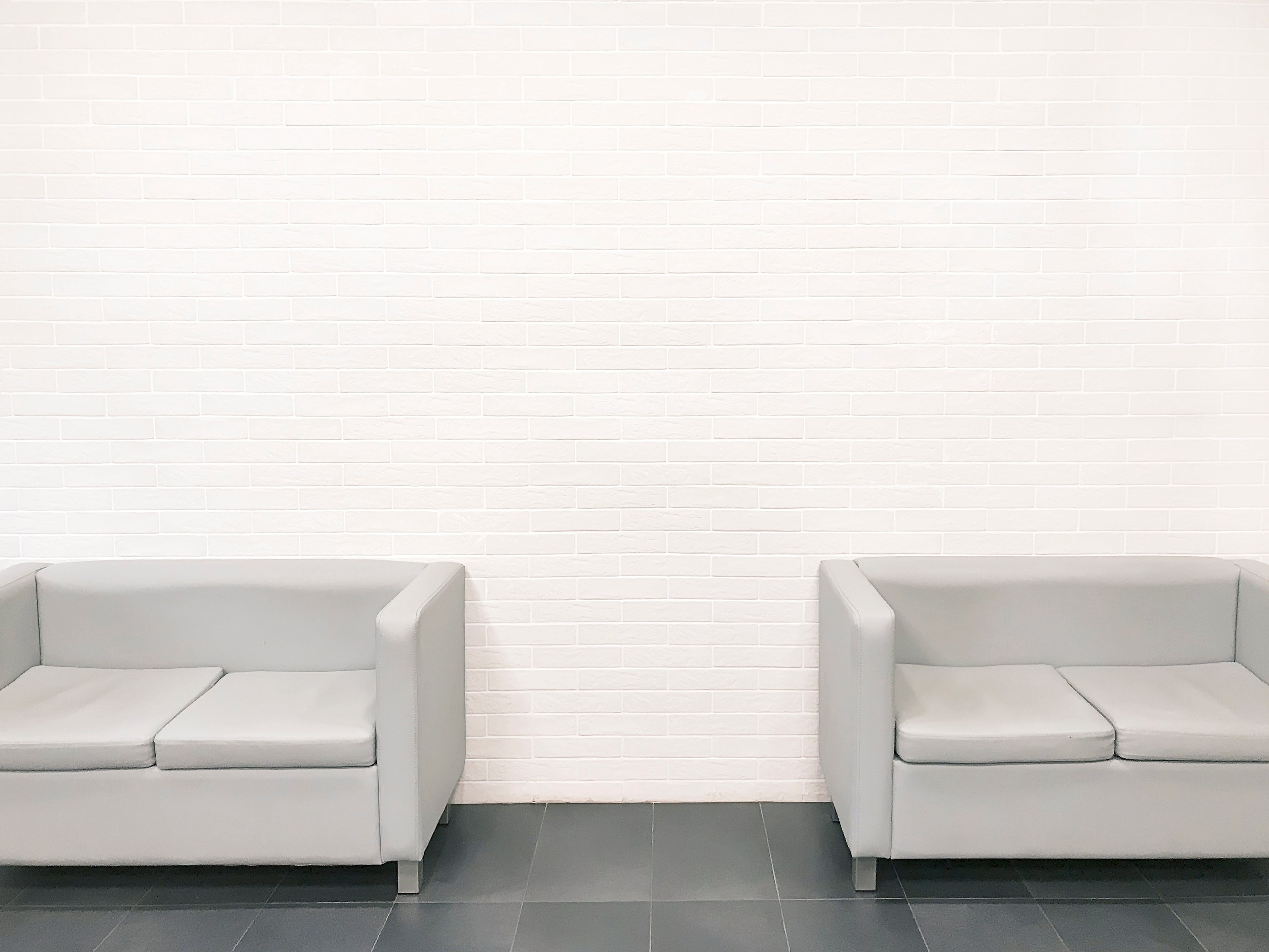 Two gray couches in a minimalistic room with a white wall. Acrylic glass decor - Vibewall